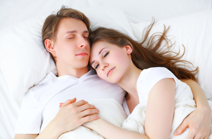 Happy couple hugging and sleeping in bed at home