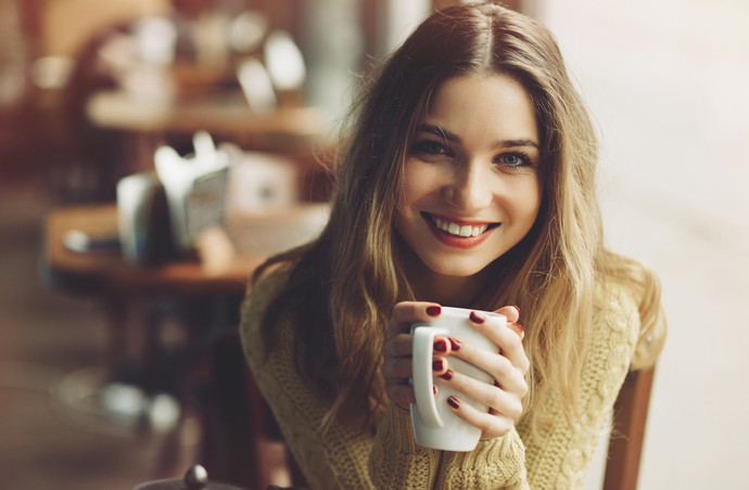 charming girl drinking cappuccino and eating cheesecake in coffee shop