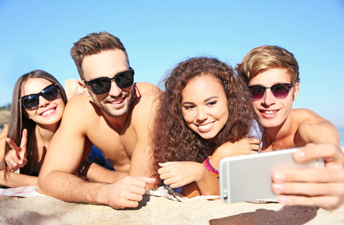 Happy friends taking selfie on beach