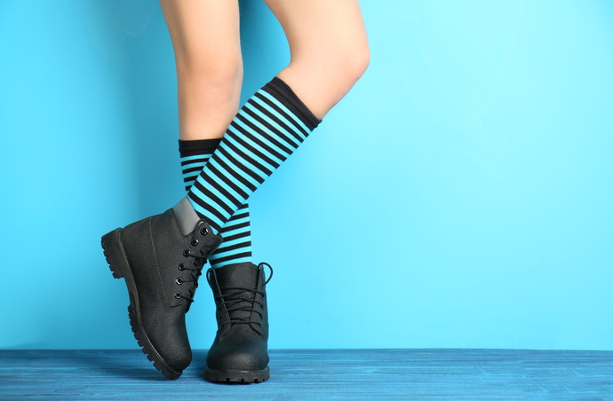 Woman in striped stockings on color background